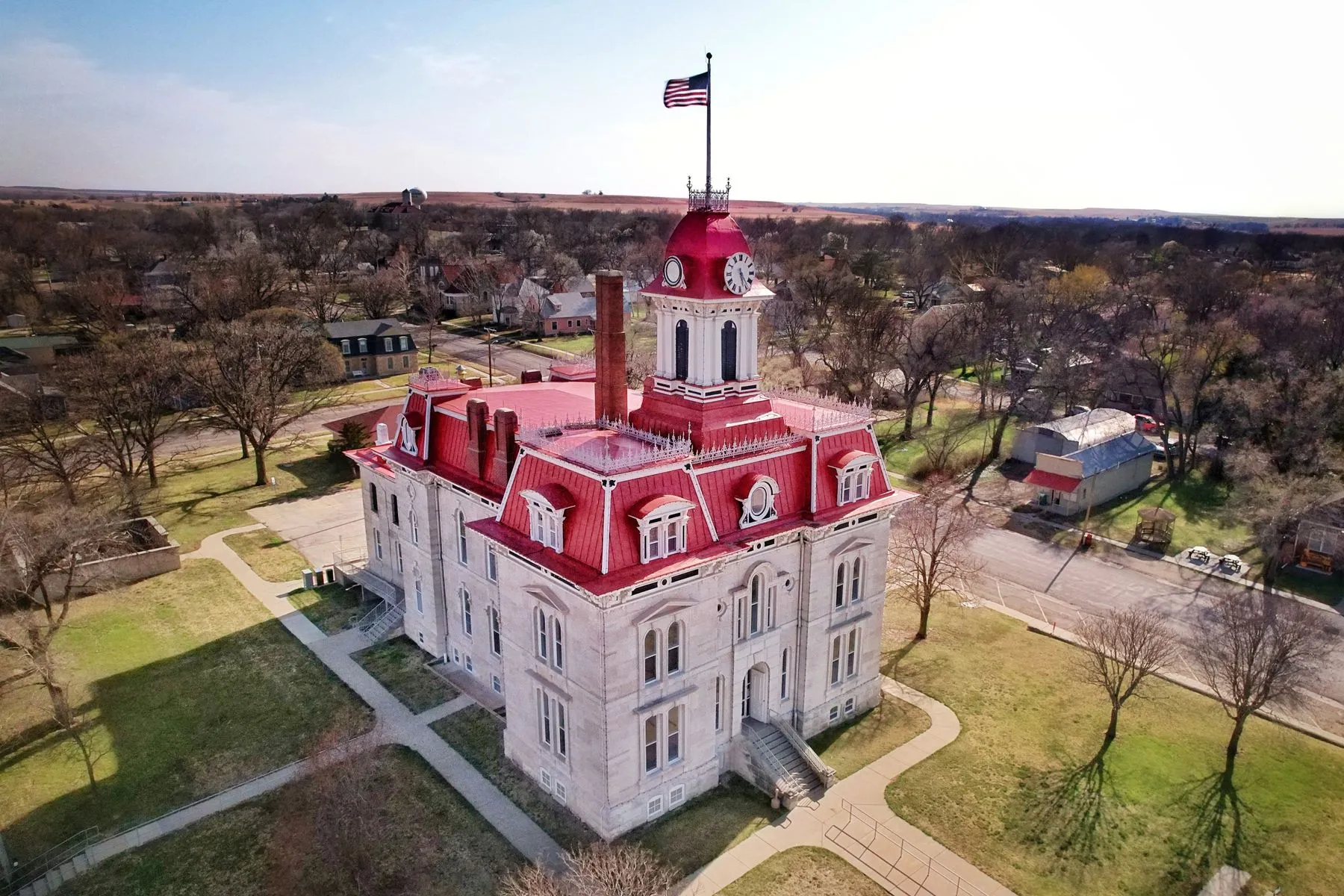 Aerial view of the Chase County Courthouse in Cottonwood Falls, Kansas, a stone building with a tower surrounded by trees and small-town streets