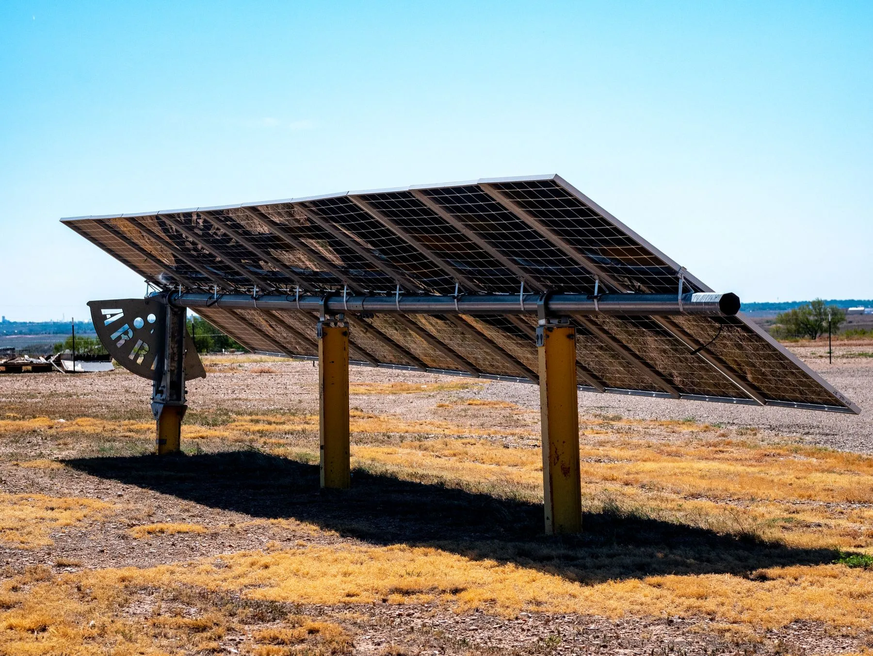 Ground-mounted solar panels under a clear blue sky on dry grassland near Amarillo, Texas